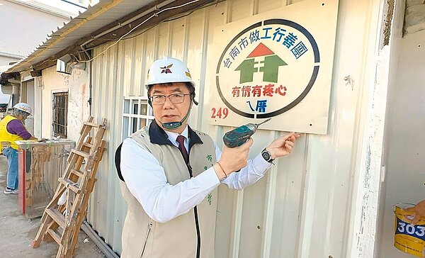 台南市政府勞工局「做工行善團」志工元旦連假到西港區為弱勢戶修屋,台南市長黃偉哲為案家掛上「做工行善團 有情有疼心ㄟ厝」圖樣木牌,象徵第249戶修繕案完工。圖/台南市政府勞工局提供