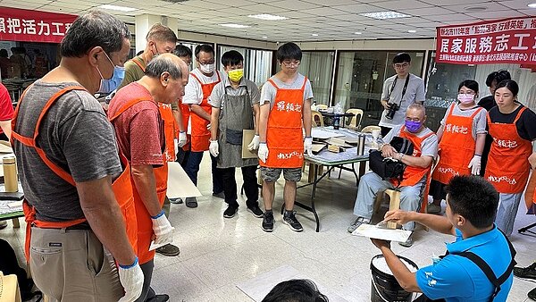 紀天明師傅向志工示範如何用批土補平牆壁的裂縫。圖/新北市政府提供