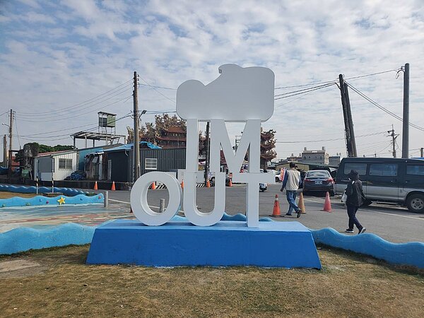 高雄彌陀漁港海岸光廊新設的「MI TUO 彌陀」裝置路標,從背後看竟變成「IM OUT」路標。記者王勇超/攝影