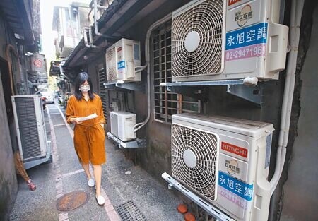 在野黨立委抨擊,電價飆漲是錯誤能源政策造成,不同意政府只想一味補助台電。圖為民眾經過許多冷氣室外機。(本報資料照片)