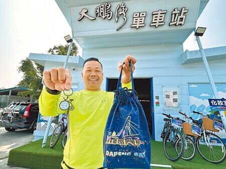 大鵬灣單車站業者羅博原響應觀光署「16條多元路線踩點Go」送紀念幣活動,加碼送單車吊飾小禮,加上鵬管處也加送小提袋,讓騎大鵬灣路線的遊客可以一次領3份禮。(謝佳潾攝)
