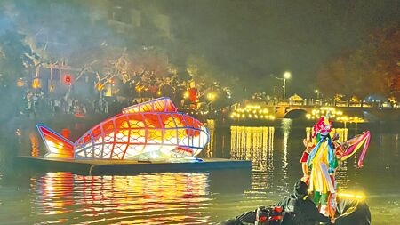 
台南鹽水月津港燈節27日晚間開幕，現場打造水上劇場，以官將首等演出，結合燈節作品，讓整體氛圍更上一層樓，許多民眾坐在岸上欣賞。（張毓翎攝）
