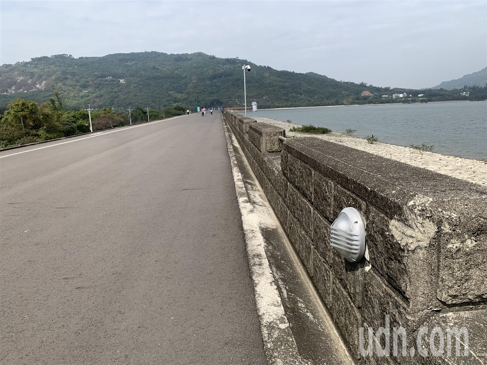阿公店水庫大壩上的防汛道路整排路燈去年7月遭工務局全數拆除,目前只能透過放浪牆上的坎燈提升照明。記者宋原彰/攝影