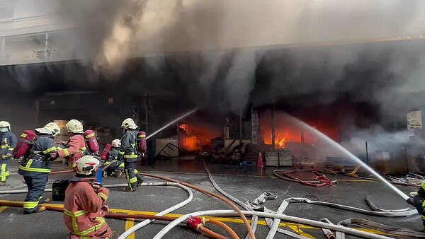 地下室竄出濃煙及火舌,延燒隔鄰2間廠房1樓,消防人員奮力灌救。記者黃子騰/翻攝