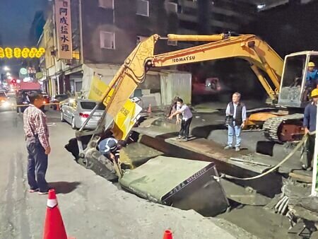 台南市西門路與五妃街口一處新建大樓工地,6日下午突發生工地旁路面塌陷,一部小貨車掉落坑洞中,圖為施工單位設法將車吊起。(寶智華攝)