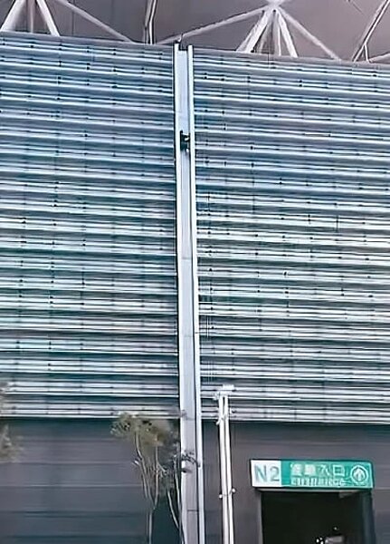 王姓男子日前潛入台北市南港展覽館二館，從樓頂沿外牆縫隙溜下，影片曝光後館方報警處理，警方依社維法裁罰王男。圖／翻攝網路
