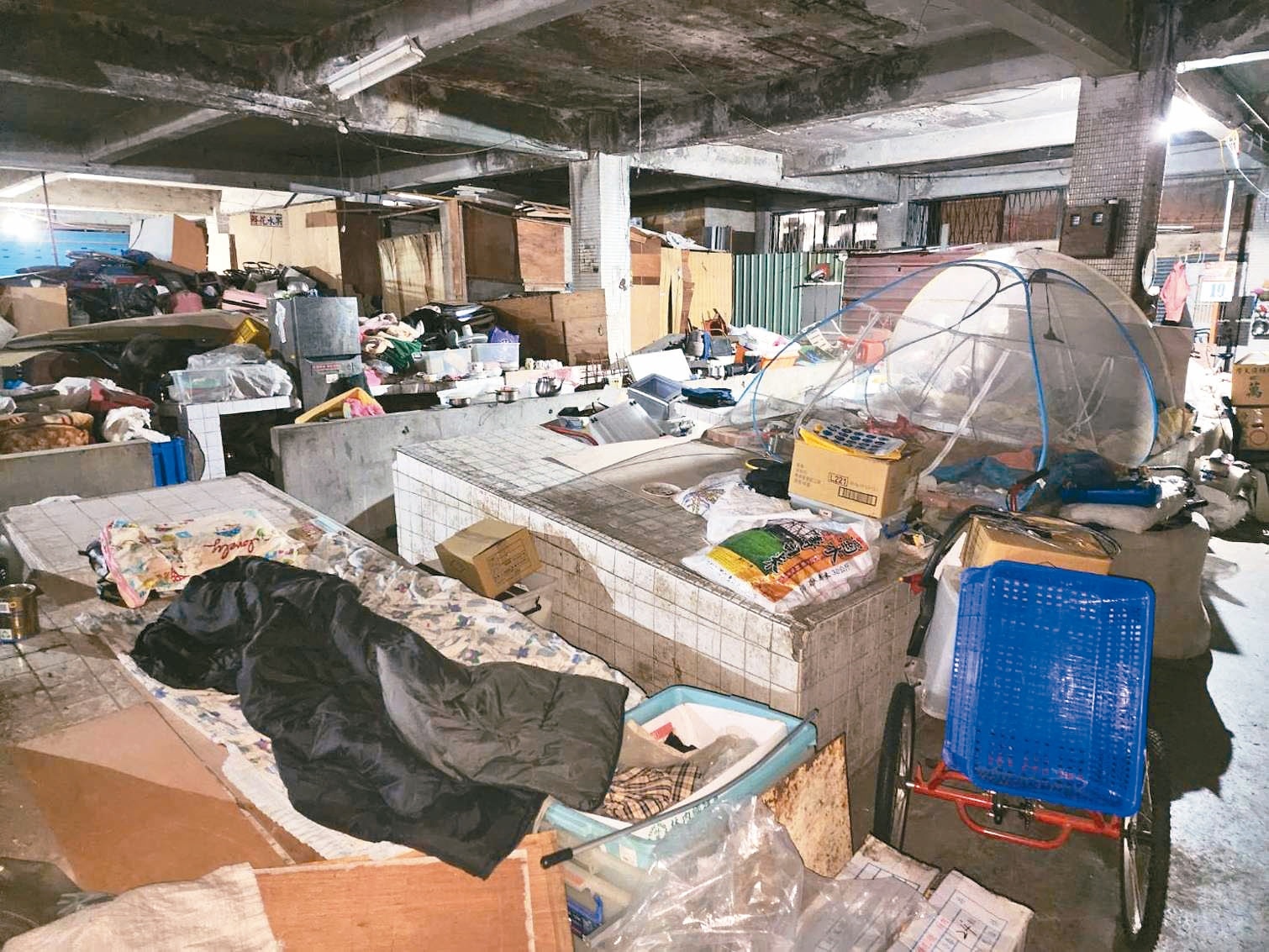 新北永和市三成功市場用地一樓攤販區內堆滿雜物，也有遊民正在雜物堆內睡覺。記者李定宇／攝影 
