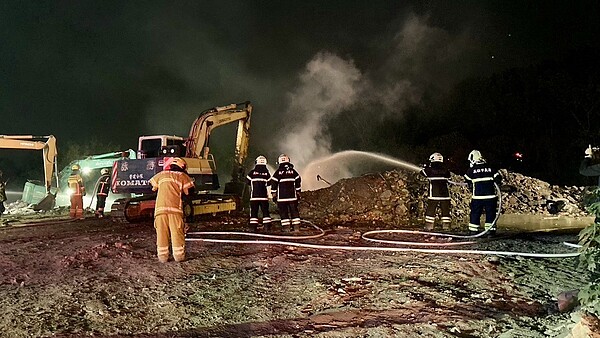 搭配現場重型機具開挖,消防員在惡臭、烈焰環境下,不斷灌水滅火。圖/記者古和純翻攝