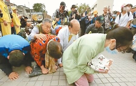 
白沙屯媽祖停駕時，醫護抱著家屬拿來的陳姓姊姊衣服，跪地祈求保佑。（孫英哲攝）
