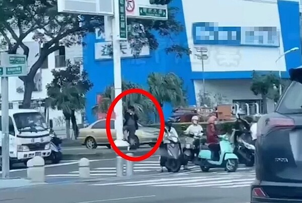 1名男子站在高雄要道拍照（紅圈處），網傳指他是「檢舉達人」。圖／擷取自黑色豪門企業
