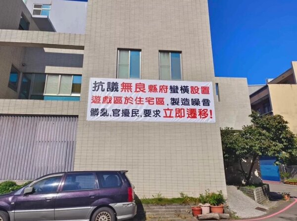 竹北市蘑菇城堡特色公園旁的居民在住家外牆掛出布條抗議，要求縣府遷移公園遊戲區。圖／讀者提供