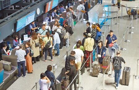 交通部宣布明年3月1日起解除大陸旅遊禁團令,各家業者將陸續推出大陸旅遊的商品。在桃園機場第二航廈出境大廳內,旅客正在排隊辦理登機手續。(范揚光攝)