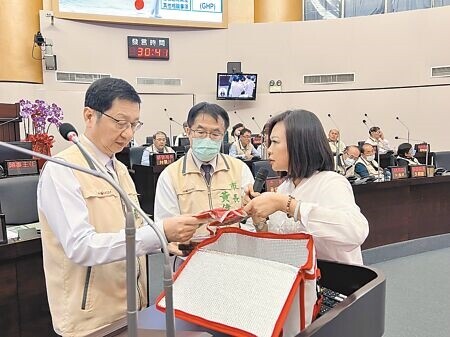 
台南市議員林燕祝（右）14日市政總質詢，拿出多包民眾在肉品市場購買的真空香腸及醃製肉片，給市長黃偉哲（中）、衛生局長蘇世斌（左）察看。（洪榮志攝）
