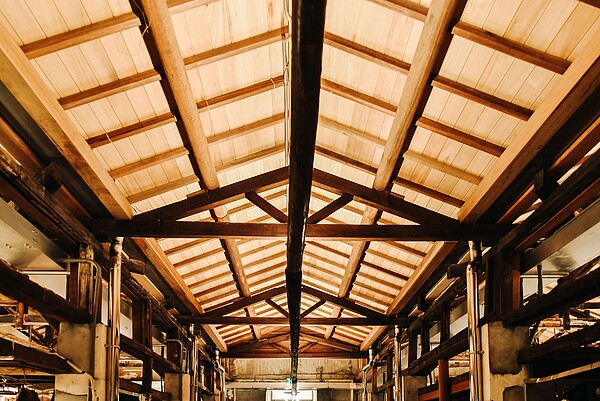 鹽一是場改造還原最初市場具歷史特色的山形木構屋頂,保留可活用的原始桁架結構及樑柱,增添新木料完善整體屋體結構,並特別保留原有木材與金屬扣件,巧妙的轉變為懸掛燈具。圖/高雄市經發局提供