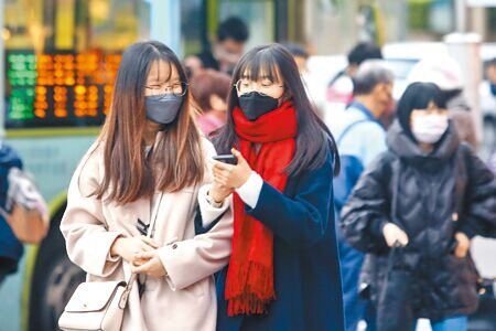今日起冷氣團報到,北部下周最低溫恐下探10度。圖為民眾戴圍巾禦寒。(本報資料照片)