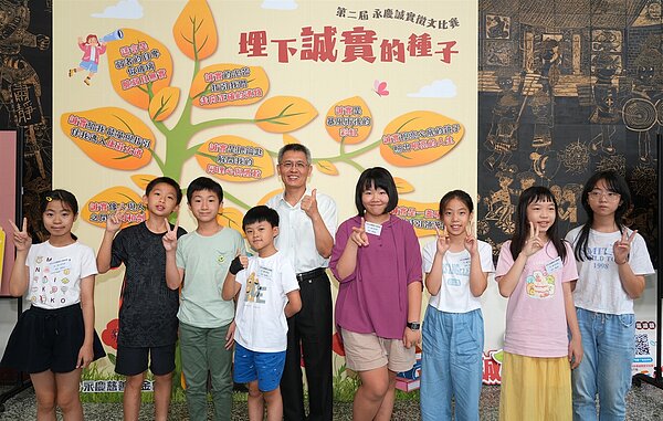 永慶誠實徵文比賽新北市區賽,新埔國小得獎人數最多,新埔國小校長陳維穎(圖中)與獲獎學生合影留念。圖/永慶房產集團提供