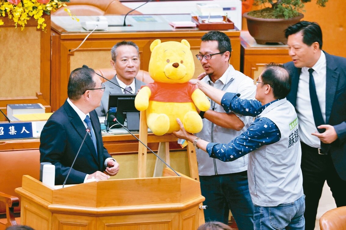 新北市議會昨市政總質詢,民進黨議員送新北市長侯友宜(左)一隻維尼熊。記者邱德祥/攝影
