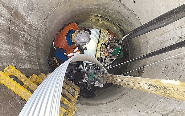 新北市水利局辦理「蘆洲南港子市地重劃區後續汙水下水道建設及既有汙水管線修繕工程」,採用免開挖工法,施工人員將材料送到人孔內部。圖/新北市水利局提供