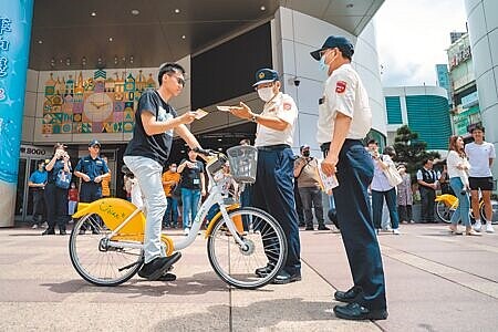 
為強化行人安全，台北市、新北市與桃園市7月1日起，共同推行YouBike違規記點制度，圖為台北市交通大隊與停管處交通助理員示範，對自行車違規進行勸導與記點。（郭吉銓攝）
