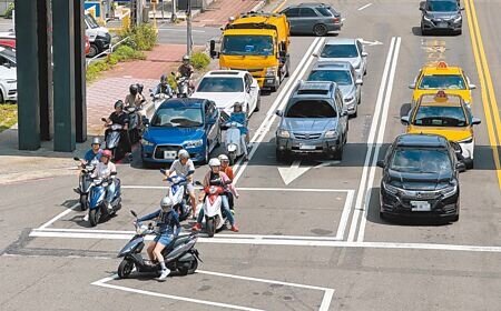 今年入夏後,高溫動輒35度,騎士停等紅燈是一大折磨,有人乖乖停在機車停等區任烈日曝曬,有人則受不了躲在樹蔭下。(陳育賢攝)