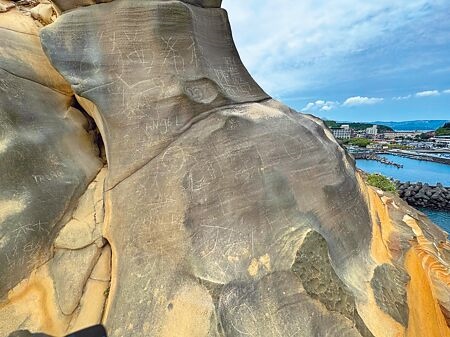 
新北市萬里區「維納斯海岸駱駝峰」6日被民眾爬上刻字，造成石頭上新增多處刻痕。（柯毓庭攝）
