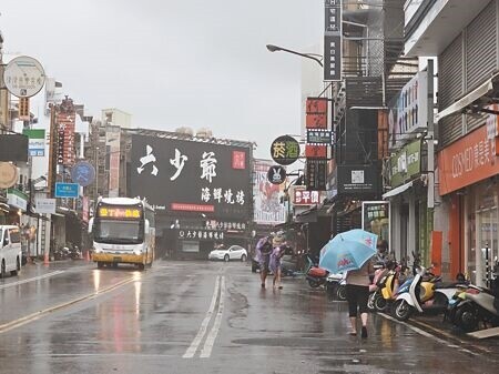 
凱米颱風來襲，墾丁大街零星遊客，穿著輕便雨衣、縮著身體匆匆走過。（羅琦文攝）
