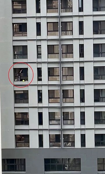 台中上午有一名婦人(紅圈處)站在豪宅高樓深窗平台上擦玻璃,驚動勞檢處人員到場調查。圖/民眾提供