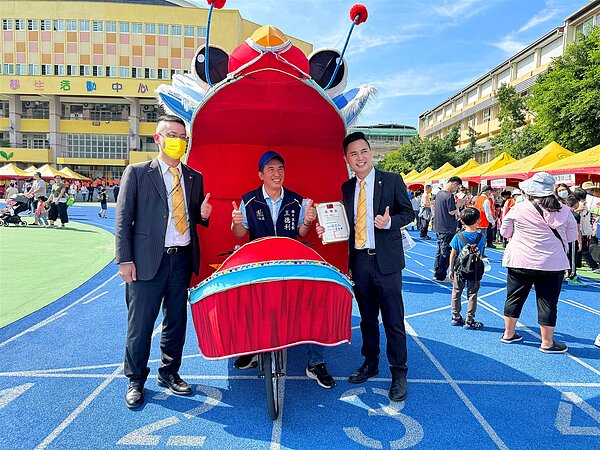 永慶房屋贊助80頂帳篷響應童玩鄰舍節,福中里里長王德利騎著台北燈會的龍型腳踏車與永慶房屋人員合照。