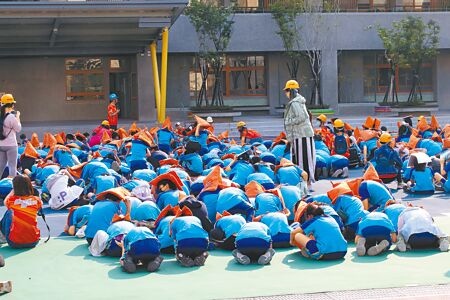 
台北市震度5級，新和國小師生緊急疏散到操場，學童也立即保護頭部就地掩護。（劉宗龍攝）
