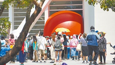 
已巡迴全球40多個城市的「紅球計畫」，3日上午在台南美術館二館展出，民眾無懼正午烈日31度高溫，大排長龍只為爭取5分鐘進入封鎖區貼近紅球合影。（寶智華攝）
