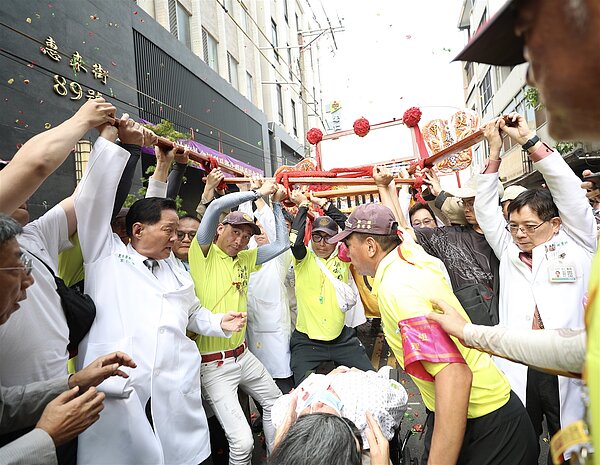 一名住院病患坐輪椅躦轎底,白袍醫師把轎抬高,為病患祈福。 圖/宏仁醫院提供