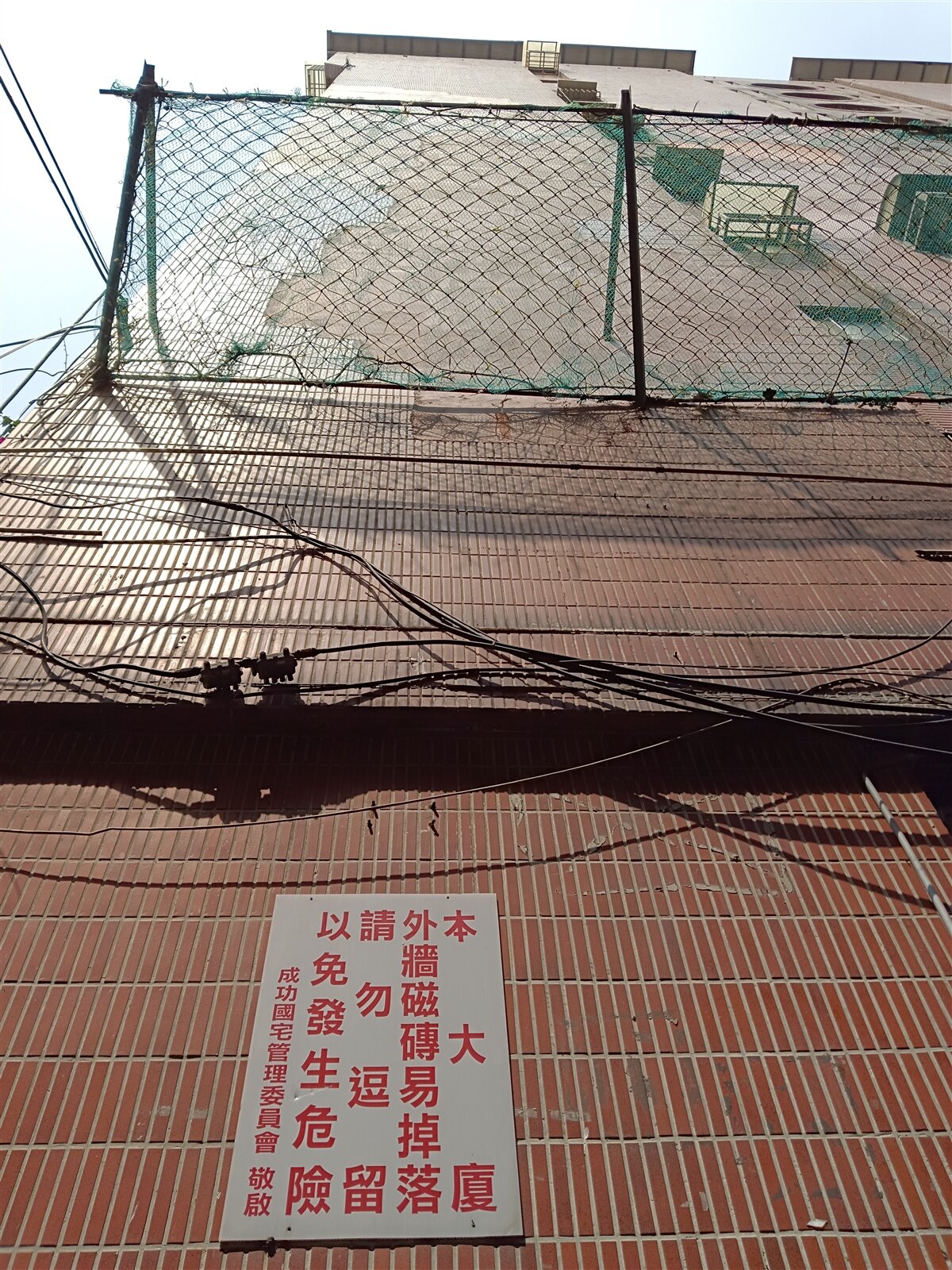 公寓大廈外牆磁磚剝落愈來愈常見,但因修繕所費不貲、整合困難,包含基隆市成功國宅社區只能先安裝防護網避免砸傷人車。記者邱瑞杰/攝影