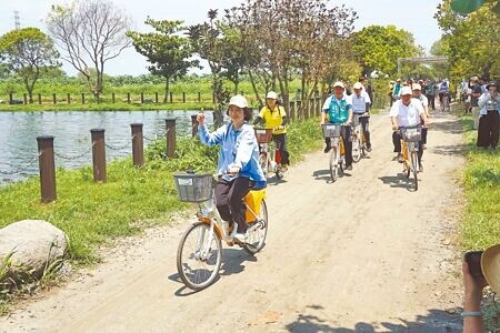 
屏東縣長周春米（前）在風景優美的海豐溼地生態池騎單車，響應世界地球日。（羅琦文攝）
