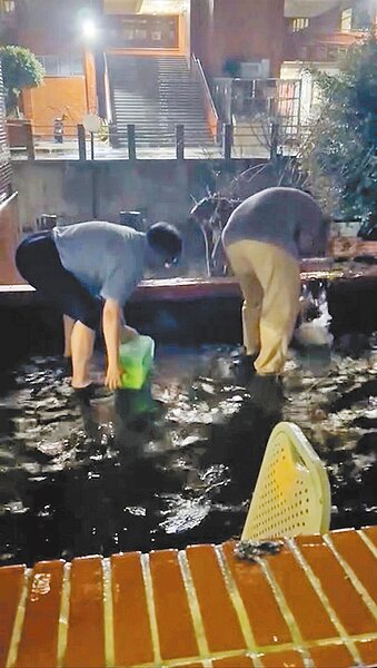 中山大學武嶺二村男生宿舍於25日傳出災情,露台出現大片積水,1人拿著水桶、1人拿著畚箕不停舀水奮力往外倒。(讀者提供/洪靖宜高雄傳真)