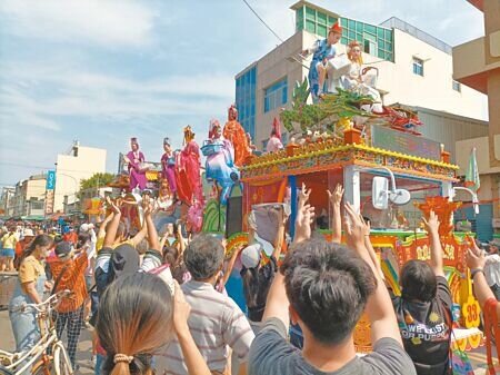雲林北港迎媽祖的真人藝閣所到之處引起圍觀,民眾紛紛伸長手,等著接藝閣上的仙女、仙人灑下糖果。(周麗蘭攝)