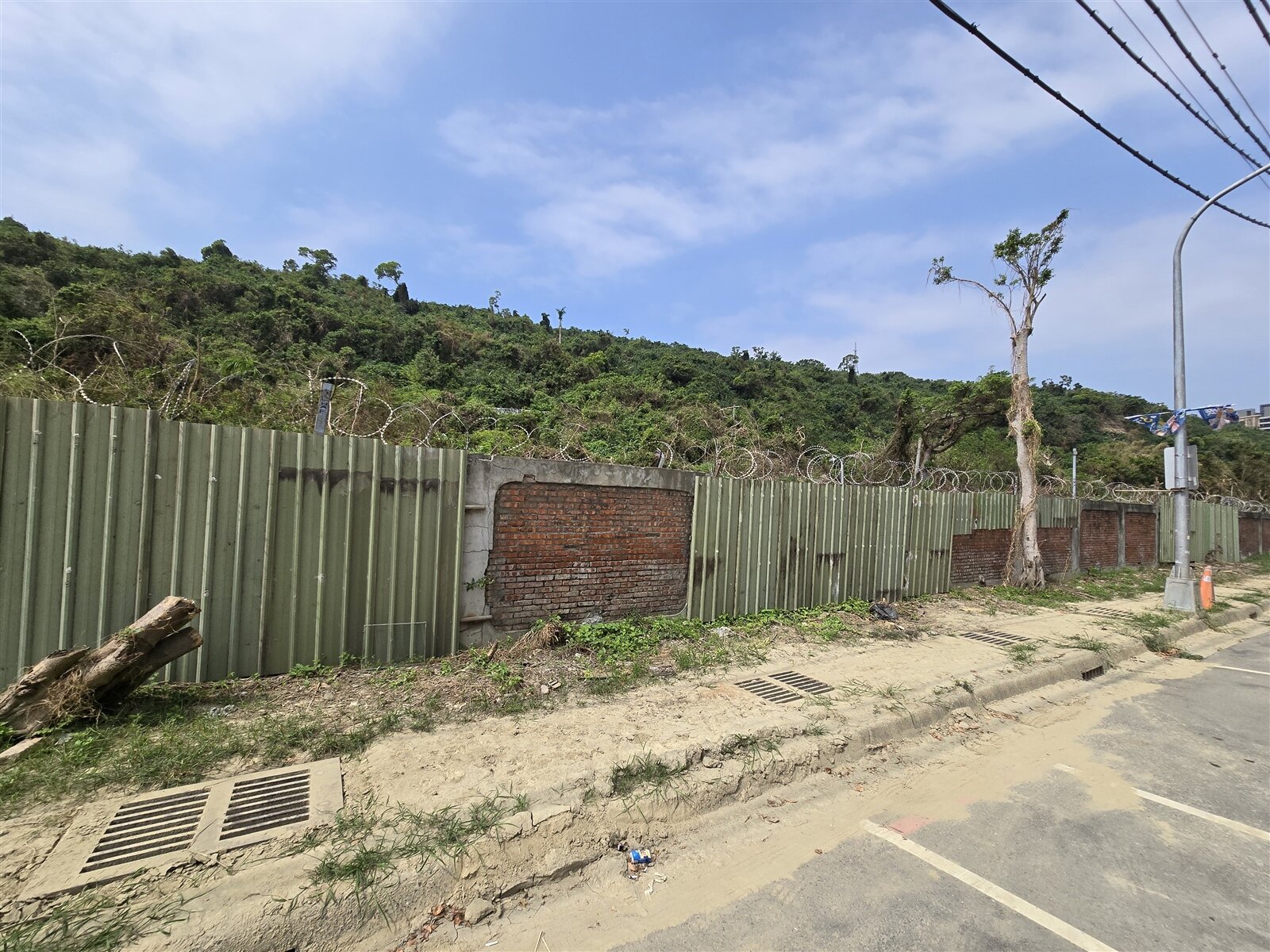 軍方已用鐵皮圍籬包圍軍營圍牆破損處，但周圍的人行道與道路仍可看到乾涸的黃泥。記者王勇超／攝影 