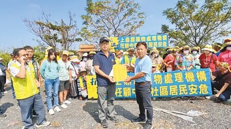 台南市安定區中榮社區100多位居民21日到廢棄物處理場申設場址旁抗議,中榮里里長翁炳煙(前排右)把陳情書遞交給南市府環保局事業廢棄物管理科科長王世為(前排左)。(張毓翎攝)