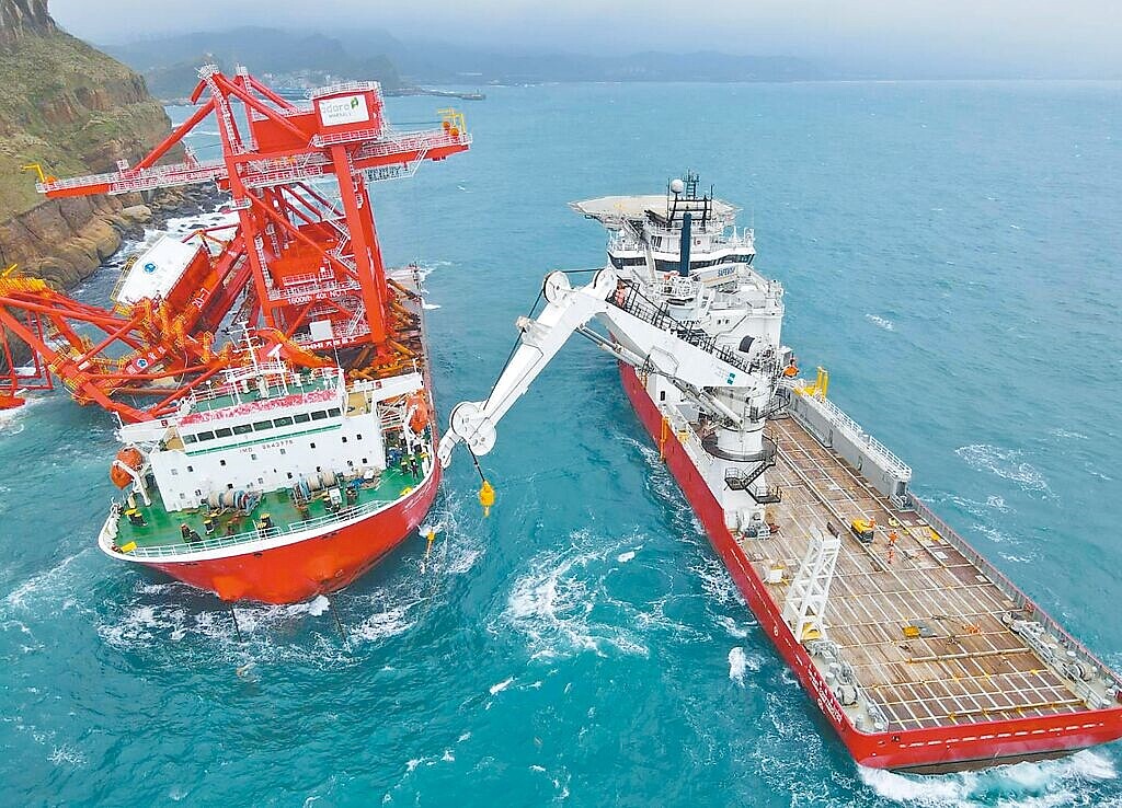 天兔颱風逼近台灣,中國貨輪「鈺洲啟航」(左)觸礁擱淺新北野柳岬。東方風能科技公司出動工程船「東方建設者」(右)在陡峭懸崖上安裝定位設備,成功將抽油設備吊掛至擱淺船上。(東方風能提供)