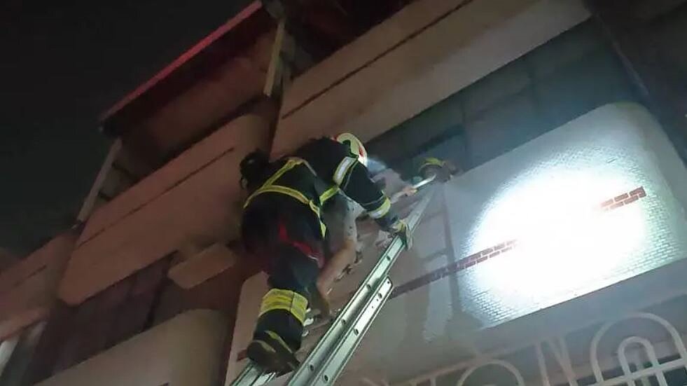 高市楠梓區朝明路民宅透天厝地下室15日晚7時45分許因雜物燃燒起火,消防員架梯救出屋內的11歲男童。記者石秀華/翻攝