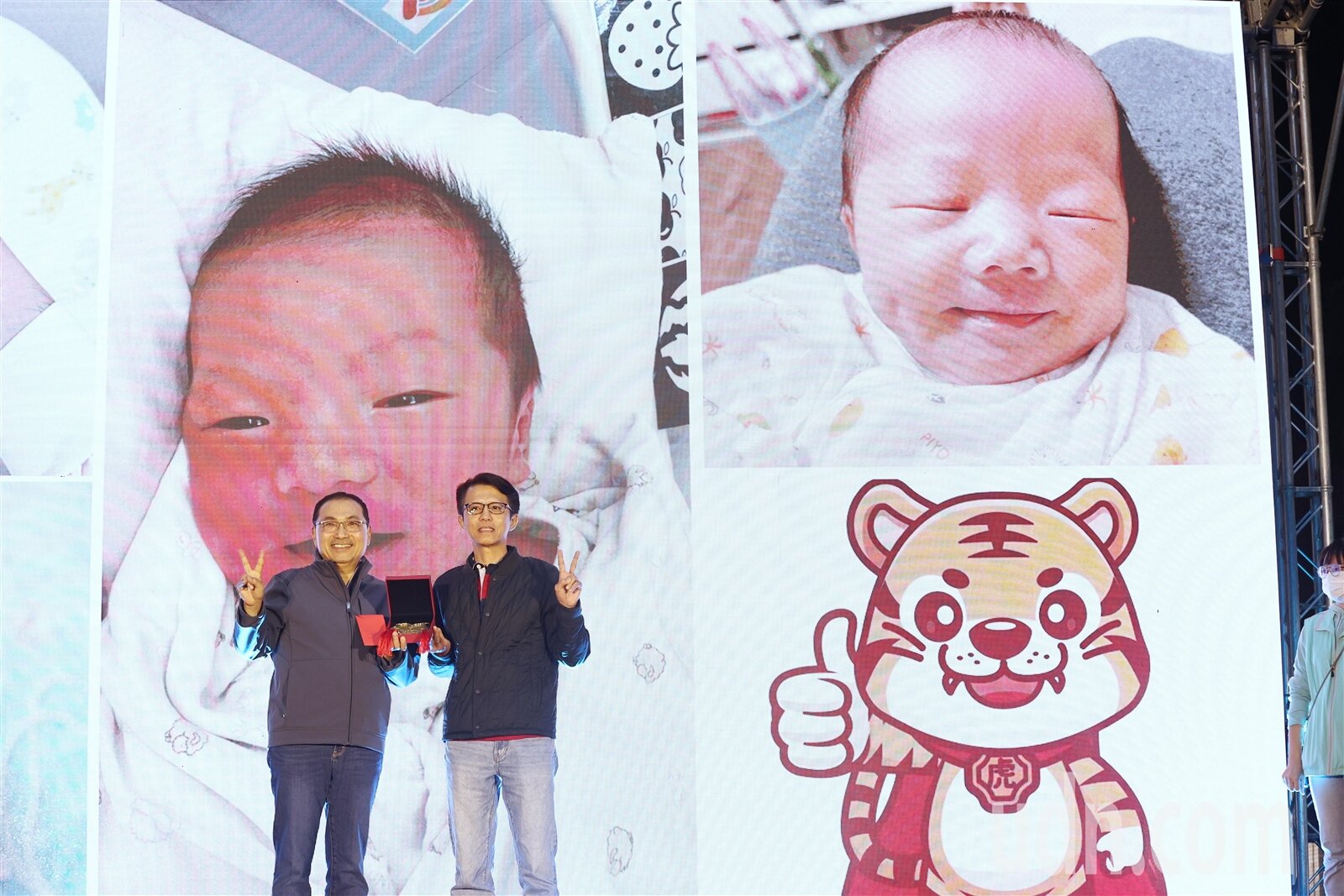 新北市長侯友宜(左)贈送給第20萬設籍淡水區的新生兒父親黃文彬(右)金飾賀禮。記者邱德祥/攝影