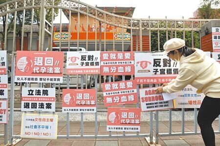 台灣女力連線與多個婦女人權團體5日在立法院門口貼上標語抗議,強調代孕目前並無社會共識,呼籲停止審查與代孕制度相關的法案內容,堅決反對將女性的子宮商品化。(鄧博仁攝)