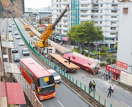 
新北市三重區台1線高架忠孝橋路段20日重大交通事故，載運鋼梁的拖板車從三重往北市方向因不明原因鋼梁翻覆，橋面與護欄嚴重毀損，也波及橋下車輛，險象環生。（陳君瑋攝）
