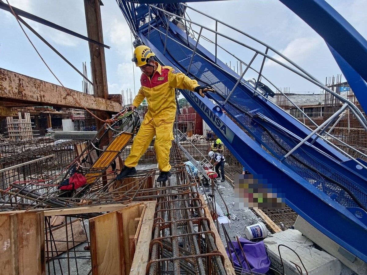 高雄三井商場工程1日上午9點多傳出工安意外，工地施工的藍色吊塔突倒塌掉落橫躺在鷹架、模板和一片鋼筋之中，意外造成工人２死；圖為消防員救援畫面。記者石秀華／翻攝
