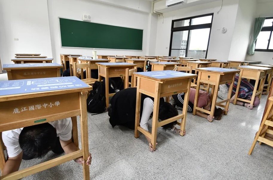 配合113年國家防災日演練活動,中央氣象署將發布全國性地震及海嘯演練防災告警細胞訊息。圖為去年9月21日國家防災日,彰化縣鹿港鎮鹿江國際中小學師生避難掩護演練,模擬地震發生後,躲在課桌下。圖/聯合報系資料照