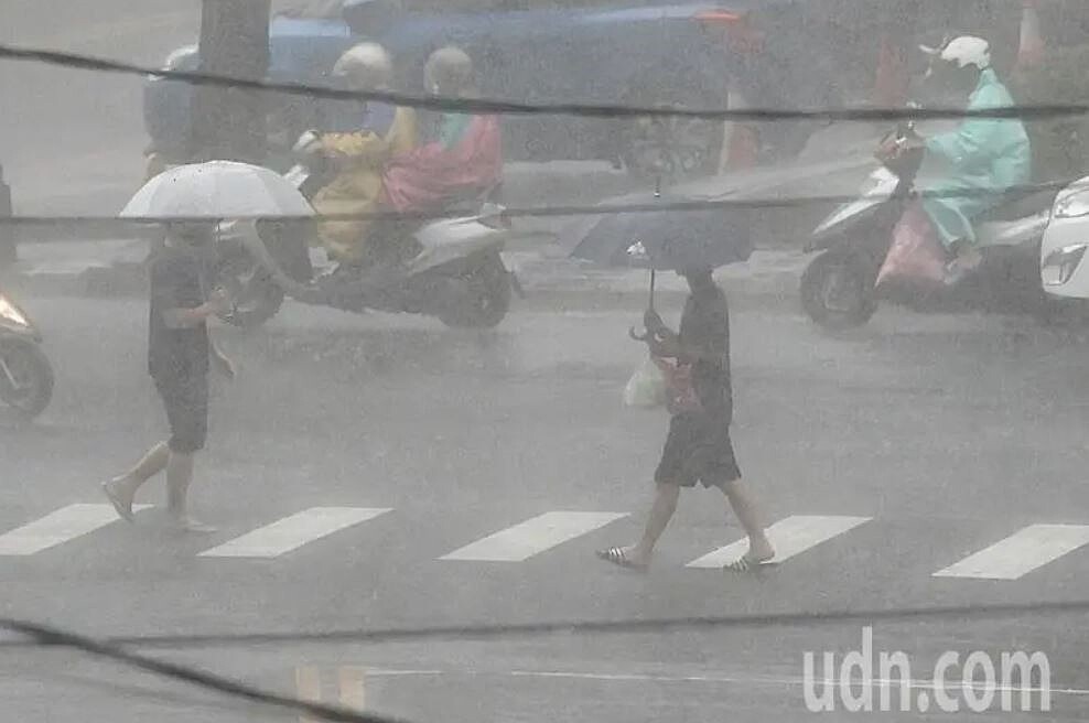 新北市中和地區上午突然大雨，讓民眾撐傘過馬路也是渾身濕答答，僅能緩步向前。記者陳正興／攝影
