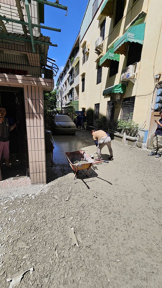 高雄市三民區建造中的大樓灌漿不慎，大量泥漿從天而降，地面、車輛全覆蓋一層水泥，居民忙著清掃路面。圖／讀者提供