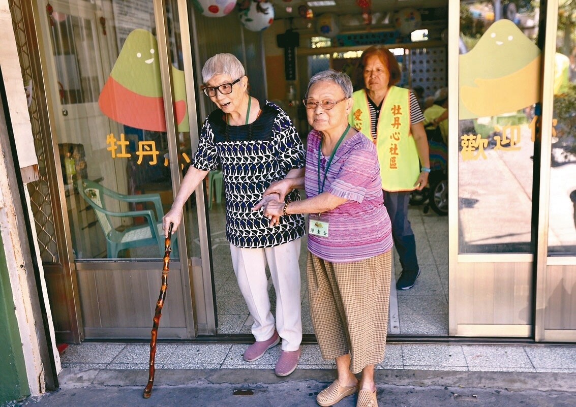 新北巿牡丹心社區關懷據點，88歲婦人陳素女（右）牽著84歲弱視的許鄭愛春上洗手間，老同學間相互扶持。記者陳正興／攝影 