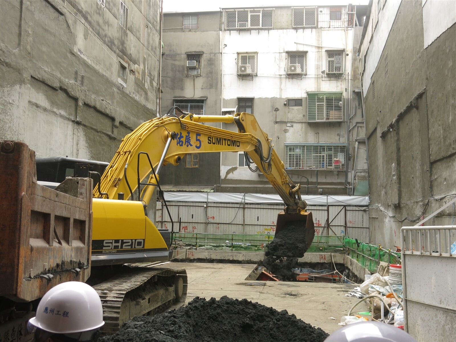 新北三重驚傳建案挖地致一旁民宅傾斜龜裂，挖土機趕緊回填土。記者李成蔭／攝影 