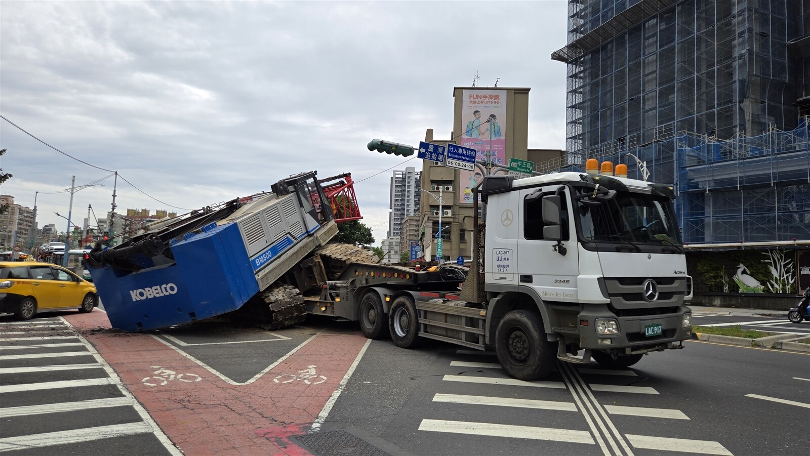 新北市蘆洲區今天中午有1輛載運大型吊車的曳引拖板車，行經捷運蘆洲站外三民、中正路口時，吊臂突然開始旋轉，導致吊車重心不穩掉落地面，發出極大聲響嚇壞許多人，幸好未傷及其他人車。記者林昭彰／攝影 