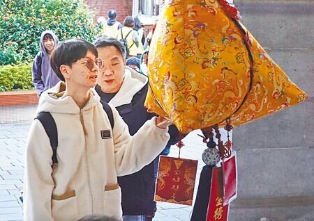 大學學測18日登場,考生及陪考家長一早抵達考場,摸了摸高掛在大門口的粽子增添好運。(姚志平攝)